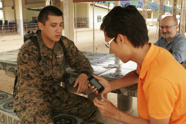 A U.S. Marine Corps petty interacts with a Thailand native using a translation application on a smartphone