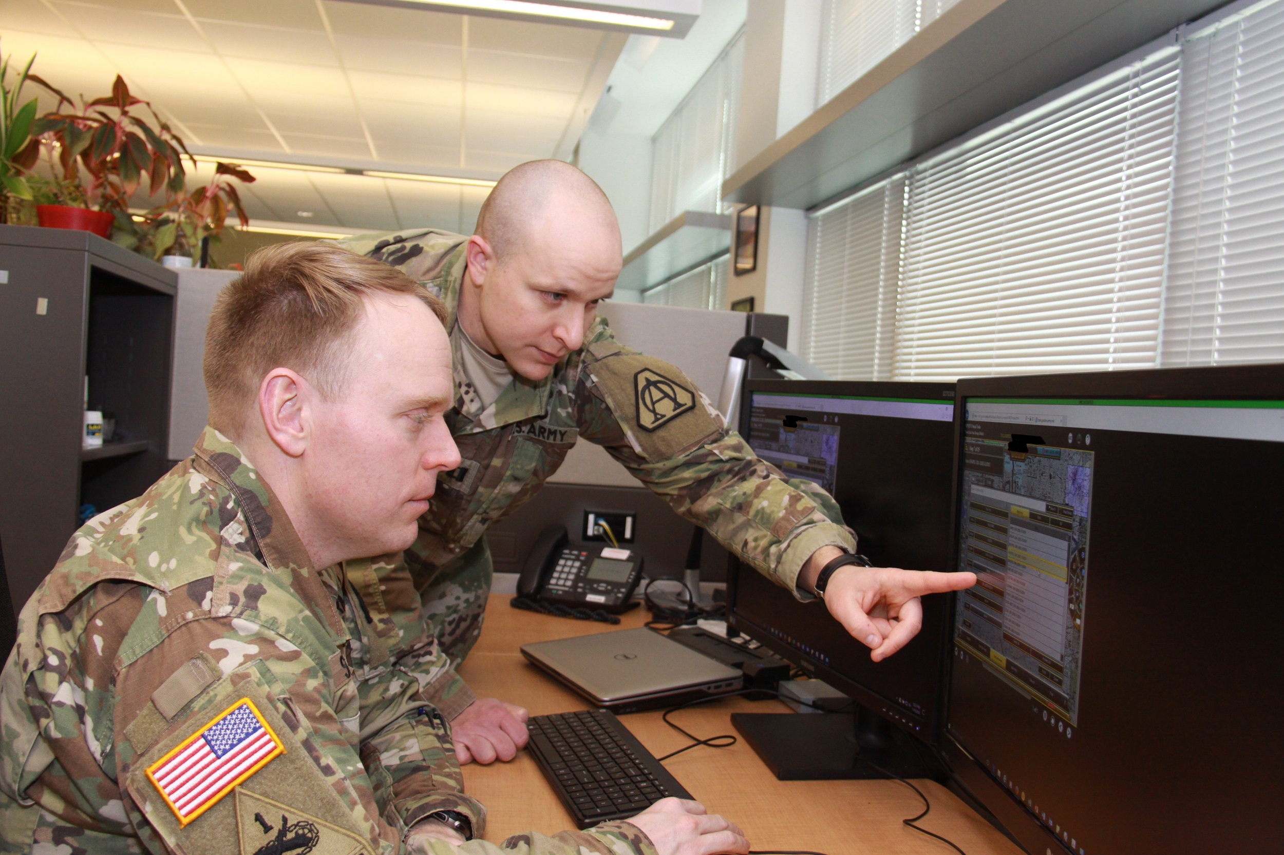 Capt. Doug Williams (standing) and Capt. Jake Singleton review the Joint Battle Command-Platform's new interactive multimedia instruction software at Aberdeen Proving Ground, Maryland, on Jan. 10, 2018. The IMI software will allow Soldiers to train on JBC-P from a CD, the Army's online training tool LandWarNet, or embedded on vehicle hardware known as Mounted Family of Computing Systems. (Photo Credit: Dan Lafontaine, PEO C3T Public Affairs)