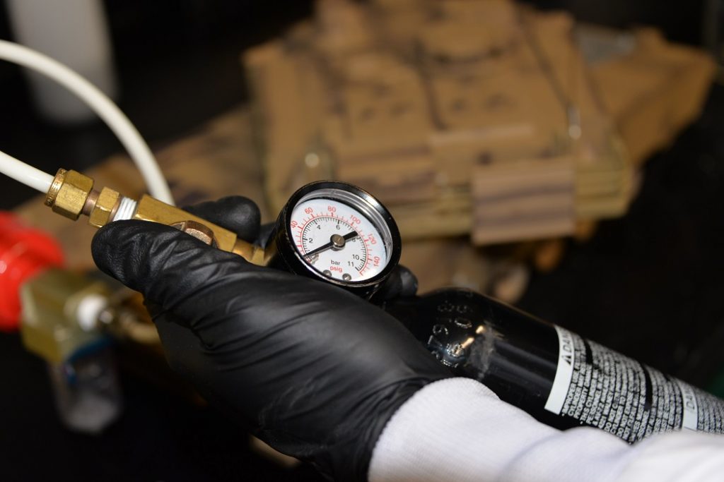 Roberts watches the pressure gauge on a fuel canister, waiting for the nanogalvanic aluminum-based powder to react with water, releasing hydrogen to power a remote-controlled tank in a demonstration. Scientists discovered this hydrogen reaction accidentally in 2017 while trying to develop an aluminum alloy. (Photos by Jacqueline M. Hames)