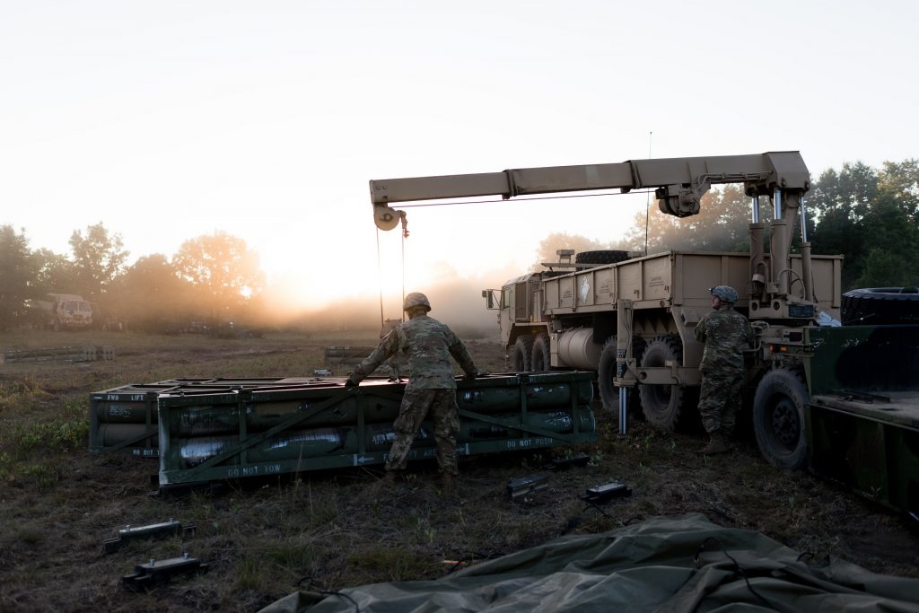Spc. Cody Jensen, truck driver, 147th Forward Support Company, 1st Battalion, 147th Field Artillery Regiment, Roslyn, S.D., guides an expended missile tube from a Multiple Launch Rocket System onto an empty truck bed as Pfc. Steven Smith, truck driver, 147th FSC, operates the winch system on Aug. 10, 2018. South Dakota Army National Guard Soldiers are participating in Northern Strike, a joint multinational combined arms live fire exercise at Camp Grayling, Mich. (U.S. Army National Guard photo by Spc. Joshua Boisvert)