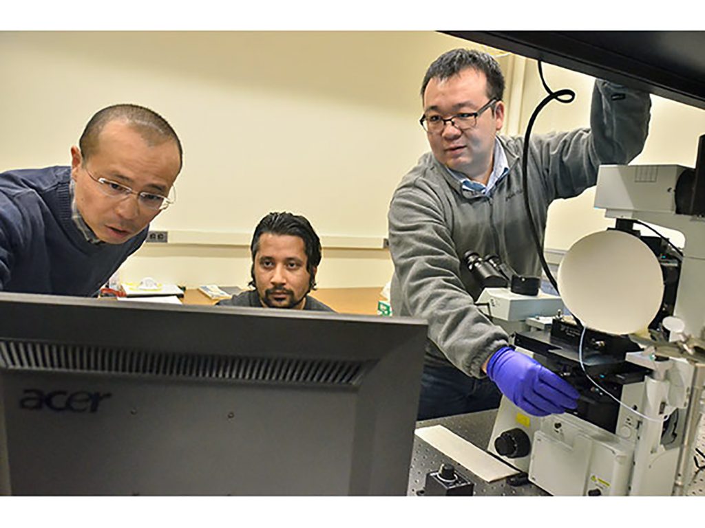 Cornell University Chemistry Professor Peng Chen, left, principal investigator in Army research that resulted in the first real-time visualization of single polymer chain growth, and Dr. Susil Baral, postdoctoral research associate, look at data while Dr. Chunming Liu, right, postdoctoral research associate, adjusts the microscope stage. In an example of the Army’s collaboration with academia on technologies critical to battlefield success, scientists at Cornell, funded by the U.S. Army Research Laboratory, researched new analytical techniques for probing polymer dynamics and how to manipulate those dynamics to control polymer microstructure. (Photo courtesy of Cornell University)