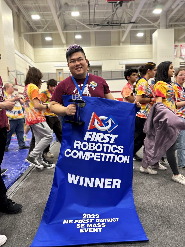 TEAMMATE TURNED MENTOR Dominic Estanislao, a mentor for the FIRST Robotics Competition Team 3314 Mechanical Mustangs, holds the winning banner at the 2023 New England FIRST Southeast Massachusetts District Event, held March 3-5, 2023, in Bridgewater, Massachusetts. (Photo by Savannah Garcia, Team 3314 Mechanical Mustangs senior)