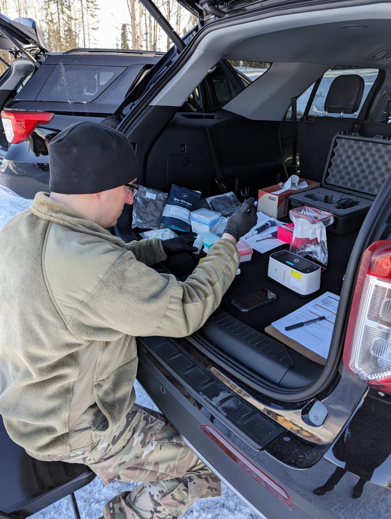 HAVE TRUNK, WILL TEST: Capt. Ian Davis of the U.S. Army Medical Research Institute of Infectious Diseases Diagnostic Systems Division conducts baseline testing in an extreme cold weather setting in the parking lot of Camp Mad Bull, Joint Base Elmendorf-Richardson, Alaska, during Exercise Arctic Edge 2024. (Photo courtesy of USAMRIID Public Affairs Office)