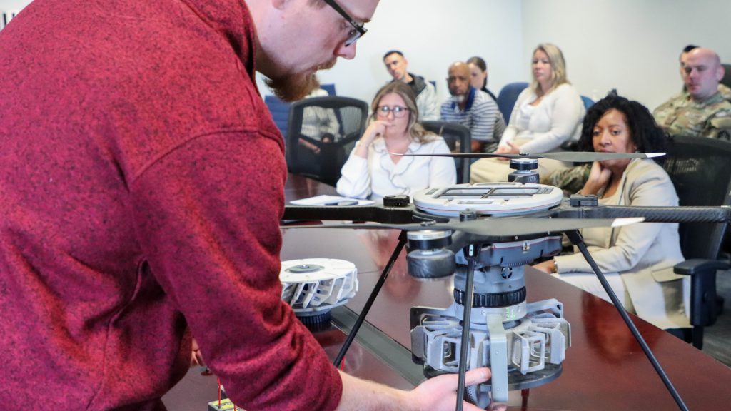 DEVCOM CBC electrical engineer James Severtsen demonstrates how the DIMES are inserted into the carousel attachment on the FLIR Skyraider quadcopter. The quadcopter can then remotely drop the expendable microsensors to create a larger system of DIMES that work together to alert warfighters of nearby threats. (Photo by Ellie White, DEVCOM CBC)