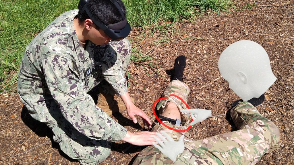 In a simulation, Navy Lt. Anh Nguyen, a master’s student who is currently evaluating the use of the IVAS augmented reality software, initiates treatment of a wounded warfighter by displaying virtual hands that provide previously recorded guidance in the procedure. (Photo courtesy of Christoph Leuze, Nakamir Inc.)